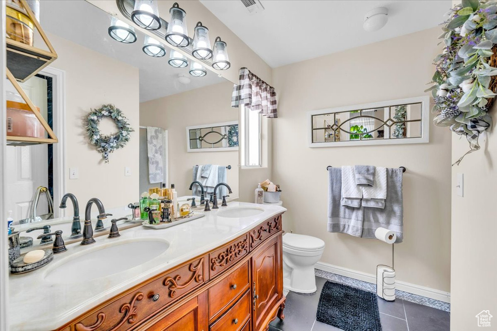 Bathroom with double sink, toilet, tile floors, and large vanity