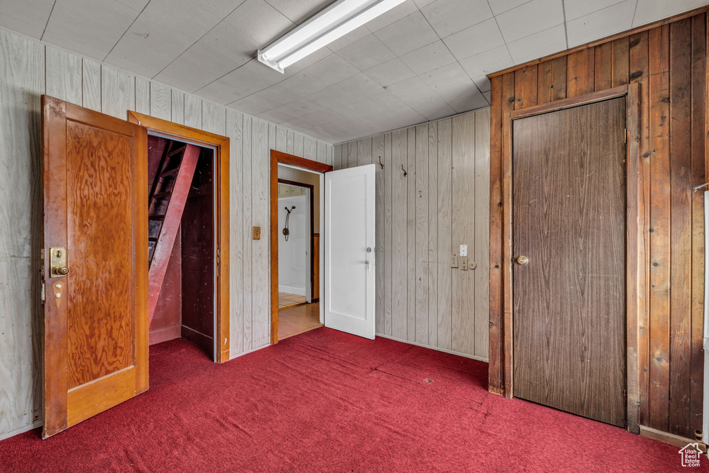 Unfurnished bedroom with wood walls and carpet flooring