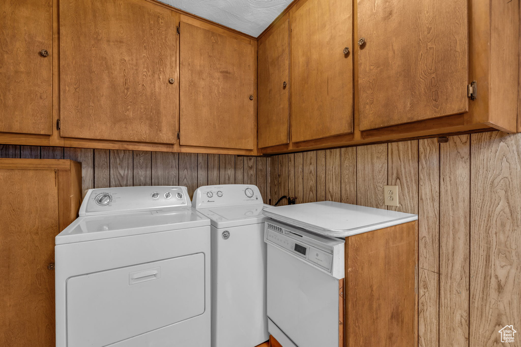 Washroom with cabinets, washer and dryer, and wooden walls