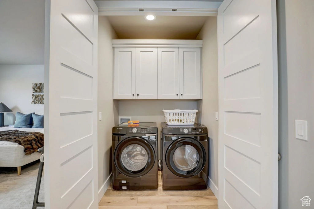 Laundry area with light hardwood / wood-style floors, washer and dryer, cabinets, and hookup for a washing machine