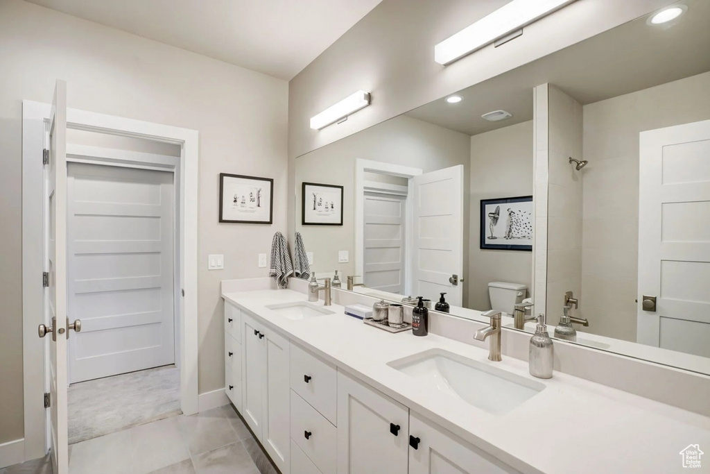 Bathroom featuring double sink vanity, toilet, and tile floors