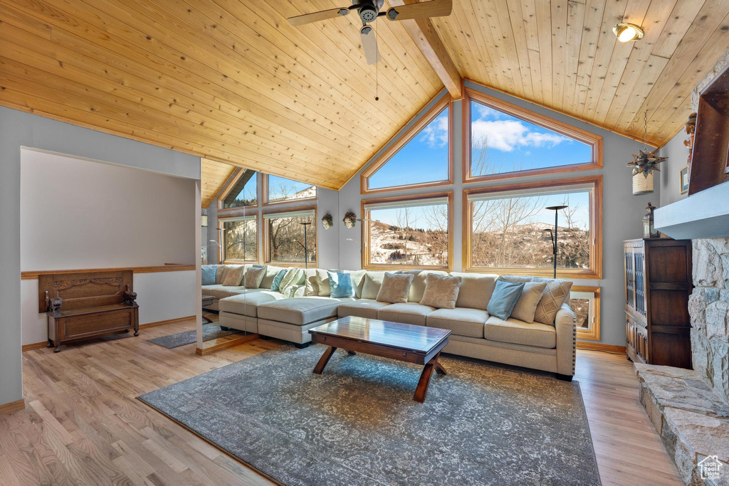 Living room with plenty of natural light, ceiling fan, beam ceiling, and high vaulted ceiling