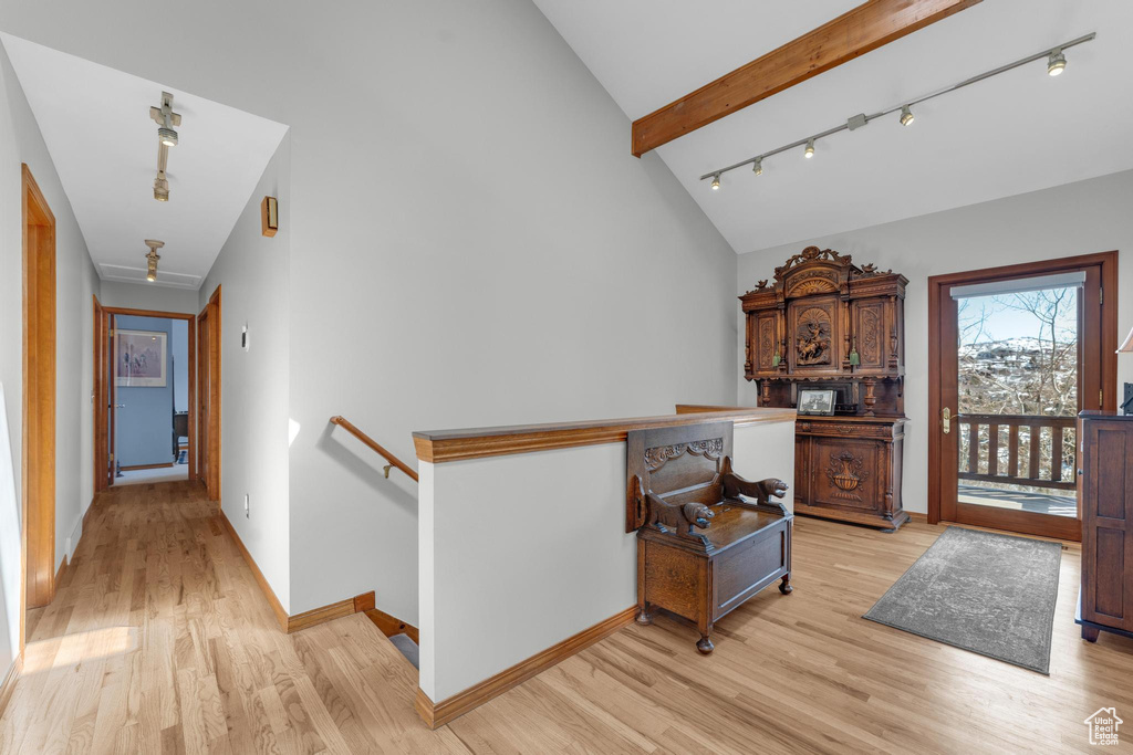 Hall with light hardwood / wood-style flooring, track lighting, and vaulted ceiling with beams