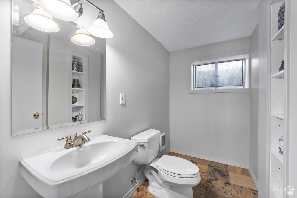 Bathroom featuring a textured ceiling, sink, and toilet
