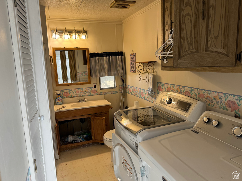 Laundry room with sink, light tile floors, and washing machine and clothes dryer