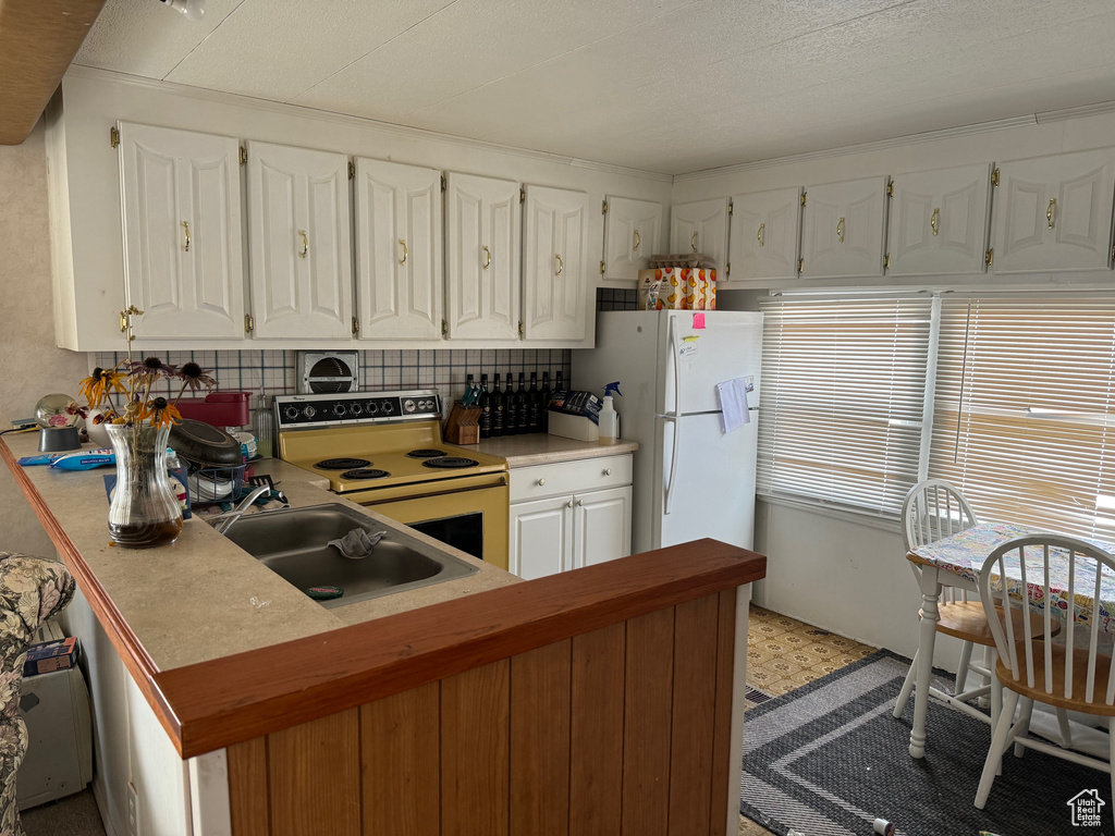 Kitchen with white appliances, tasteful backsplash, sink, and white cabinetry