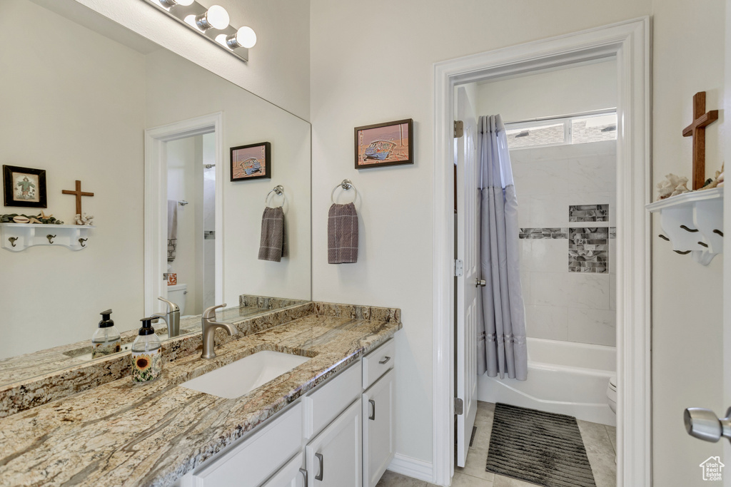 Full bathroom with tile flooring, vanity, toilet, and shower / bath combo with shower curtain