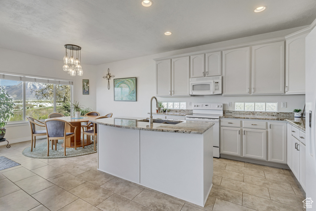 Kitchen with white cabinets, white appliances, pendant lighting, and light stone countertops