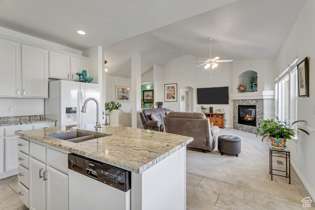 Kitchen with dishwasher, an island with sink, white cabinetry, and light stone countertops