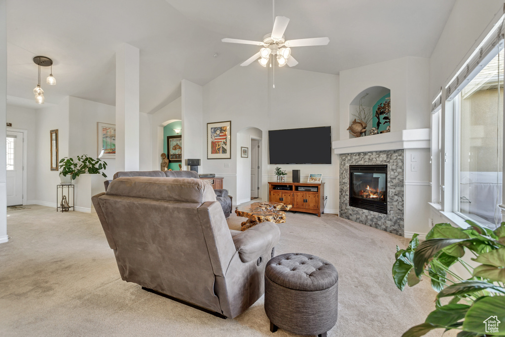 Living room with a wealth of natural light, light colored carpet, a tile fireplace, and ceiling fan