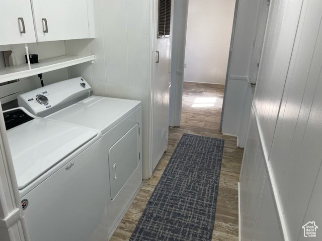 Laundry area with independent washer and dryer, light hardwood / wood-style flooring, and cabinets