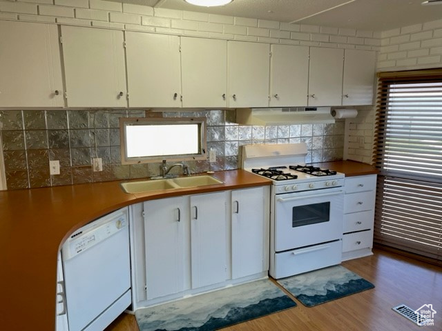 Kitchen with fume extractor, white appliances, wood-type flooring, white cabinets, and sink