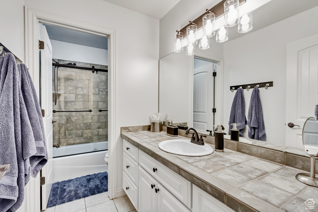 Full bathroom with shower / bath combination with glass door, large vanity, tile floors, and toilet