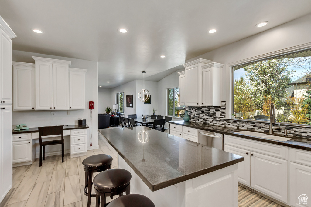 Kitchen with a kitchen breakfast bar, decorative light fixtures, white cabinets, and sink