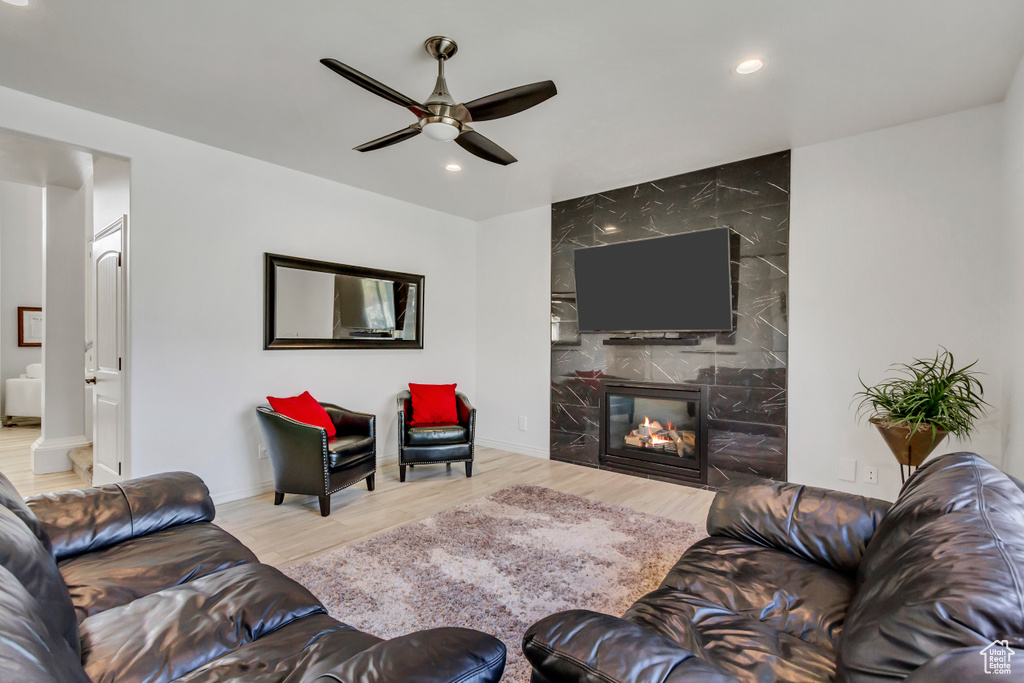Living room featuring light hardwood / wood-style flooring, ceiling fan, and a tiled fireplace