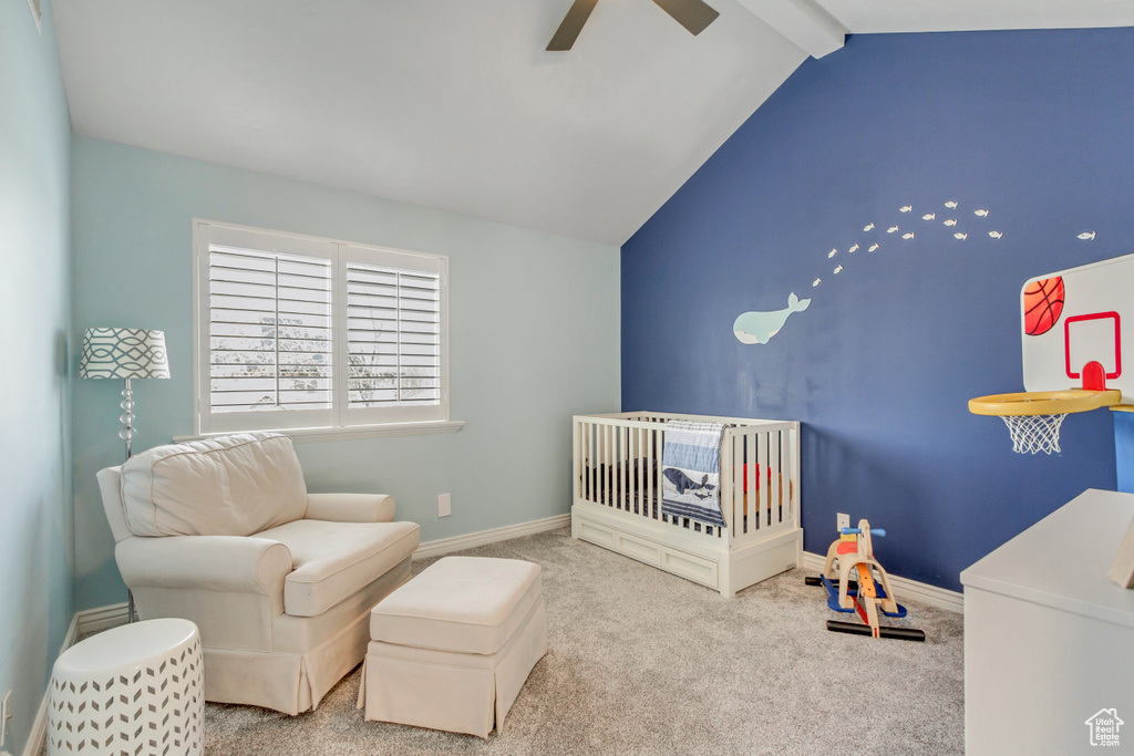 Bedroom with light colored carpet, ceiling fan, vaulted ceiling with beams, and a crib