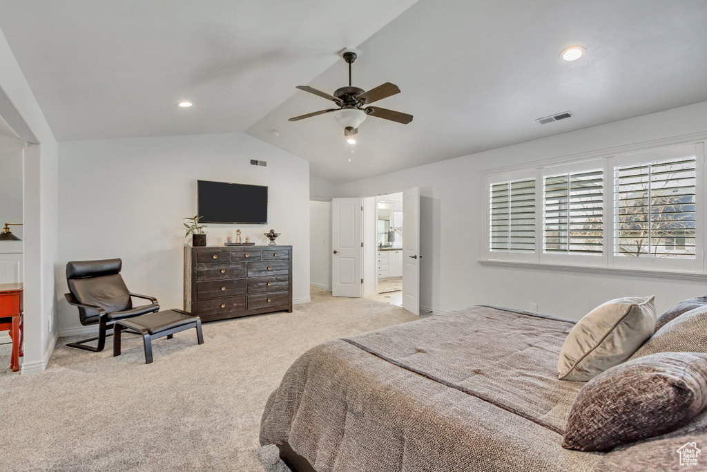 Carpeted bedroom featuring connected bathroom, vaulted ceiling, and ceiling fan