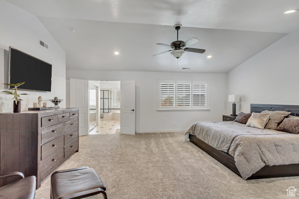 Carpeted bedroom with connected bathroom, vaulted ceiling, and ceiling fan