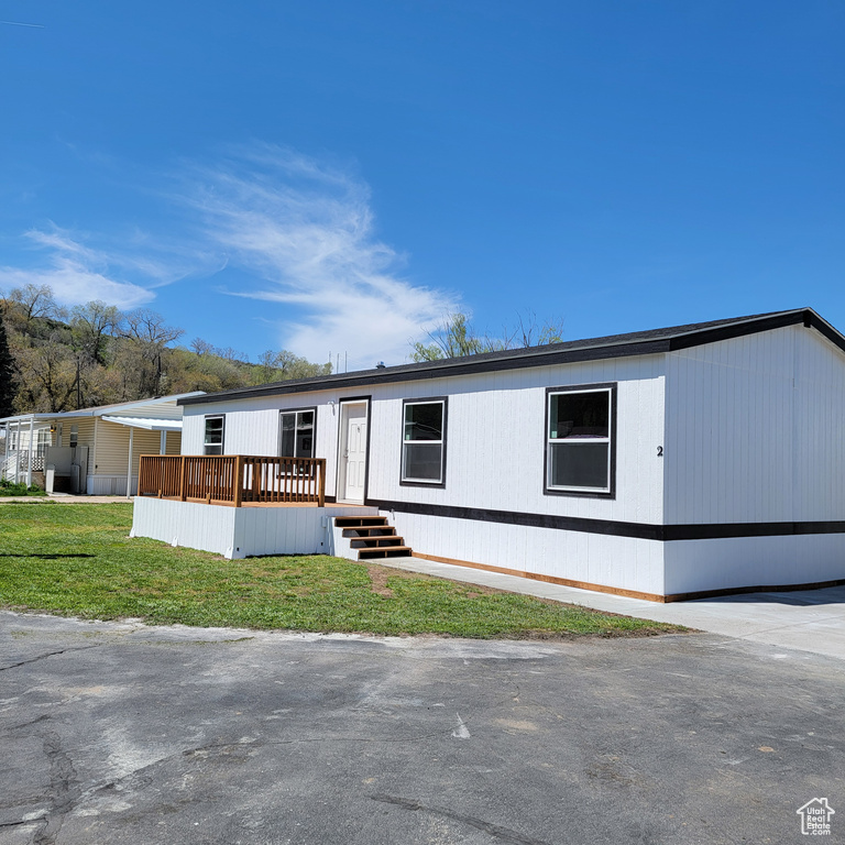 Manufactured / mobile home with a wooden deck and a front lawn