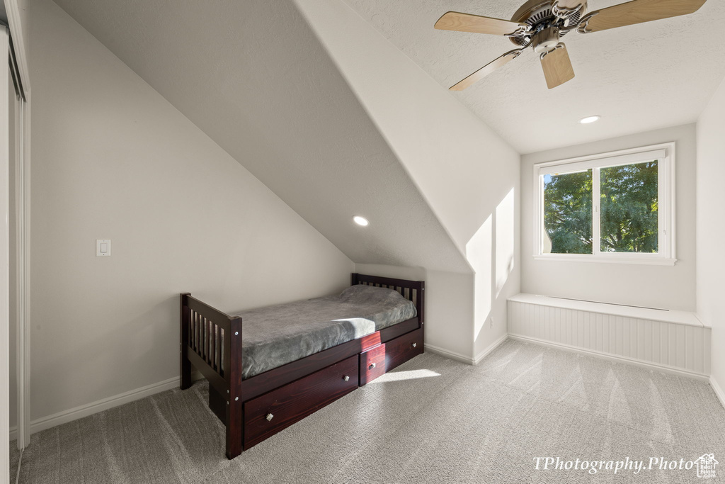 Carpeted bedroom featuring lofted ceiling, ceiling fan, and a textured ceiling