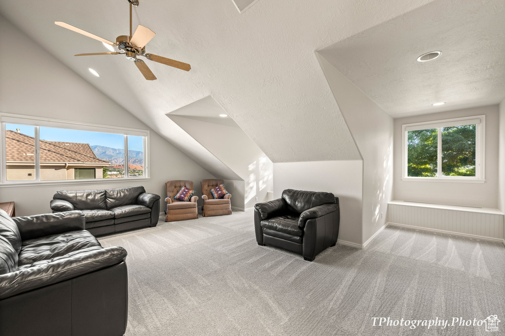 Living room featuring light colored carpet, vaulted ceiling, and ceiling fan