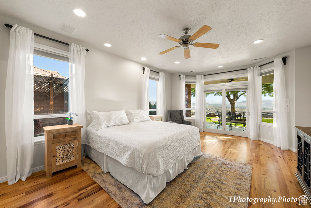 Bedroom featuring access to outside, light hardwood / wood-style floors, ceiling fan, and multiple windows