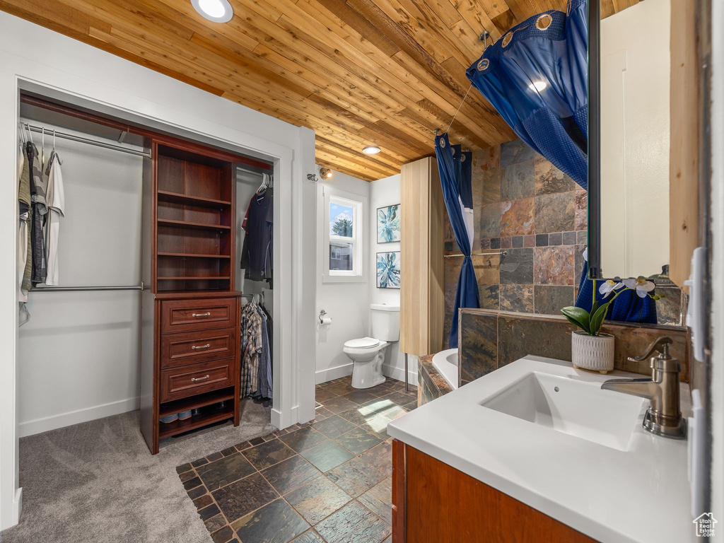 Bathroom with wood ceiling, toilet, tile floors, and vanity