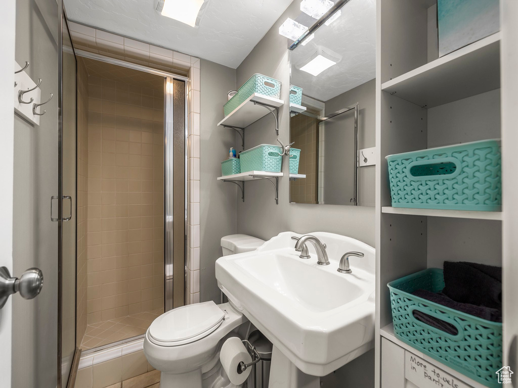 Bathroom with a shower with door, sink, and toilet