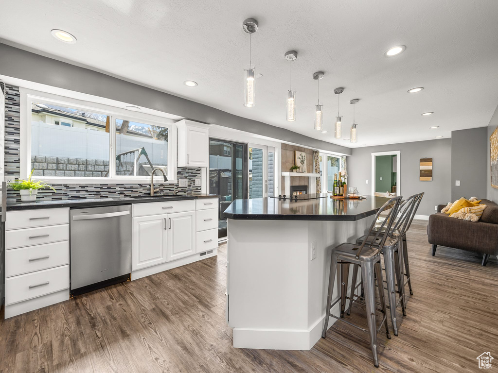 Kitchen featuring decorative light fixtures, dark wood-type flooring, white cabinetry, tasteful backsplash, and dishwasher