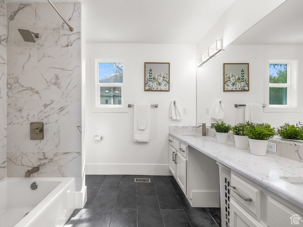 Bathroom featuring tile flooring, plenty of natural light, tiled shower / bath combo, and large vanity