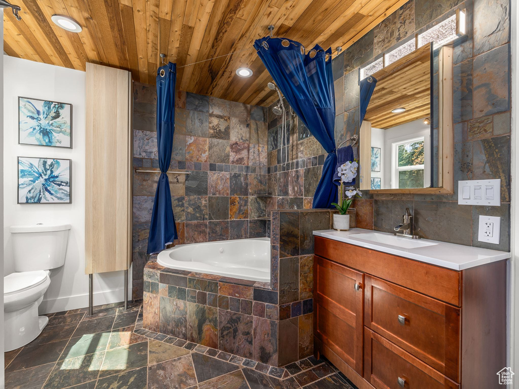 Bathroom featuring tiled tub, vanity with extensive cabinet space, toilet, tile flooring, and wood ceiling