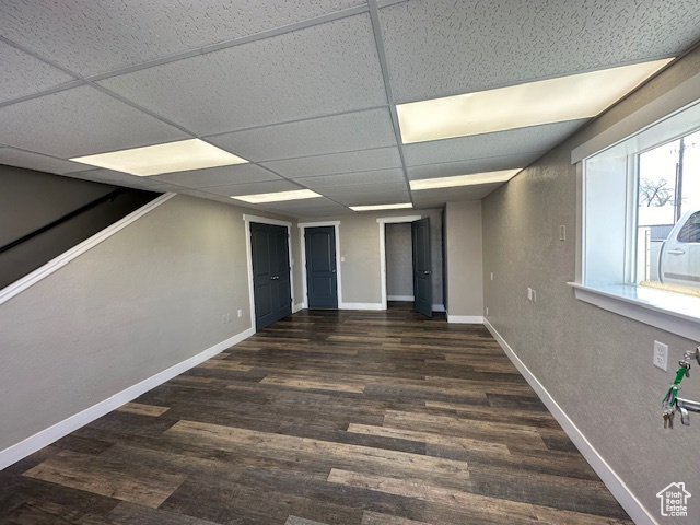 Unfurnished room with a drop ceiling and dark hardwood / wood-style floors