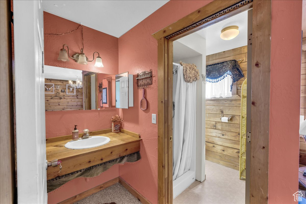 Bathroom featuring wooden walls, large vanity, and an inviting chandelier