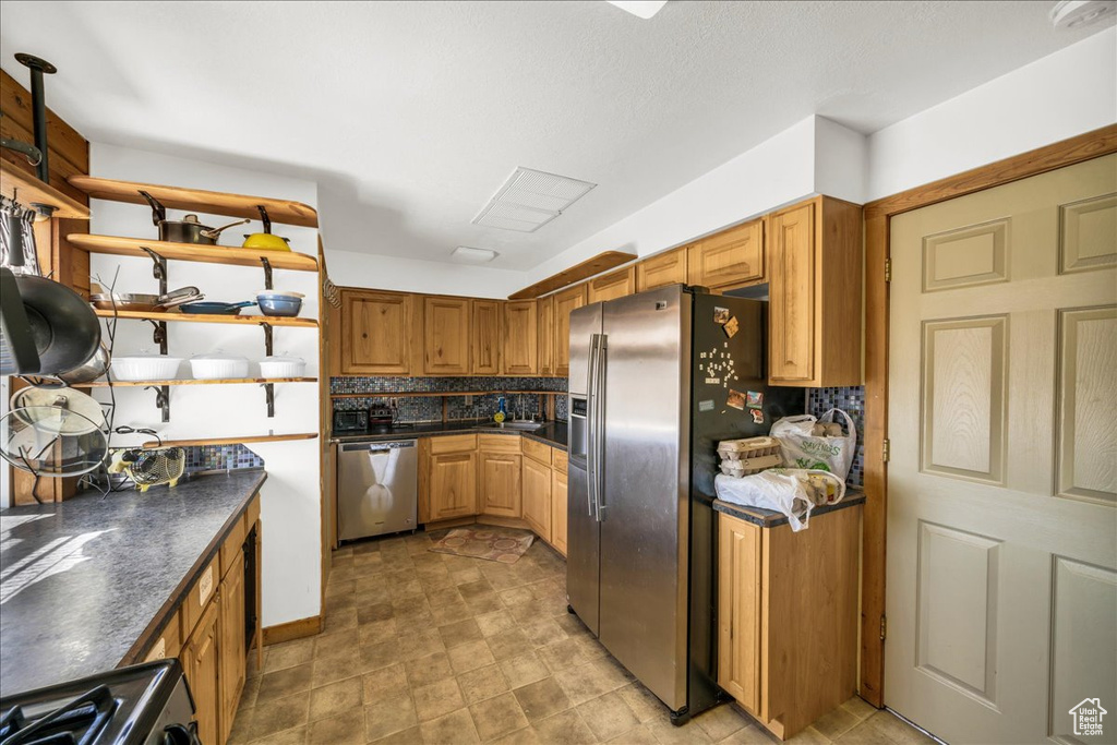 Kitchen with backsplash, stainless steel appliances, and light tile flooring