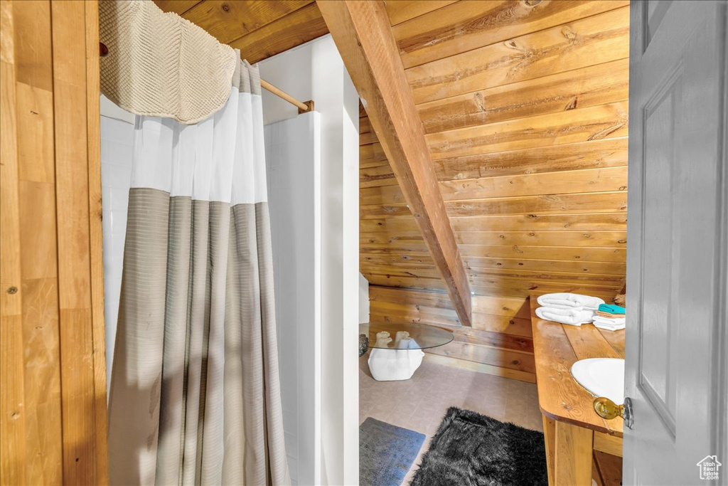 Bathroom with wooden ceiling, vanity, beamed ceiling, and wooden walls