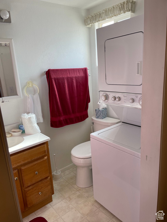 Interior space featuring tile floors, toilet, stacked washing maching and dryer, and vanity