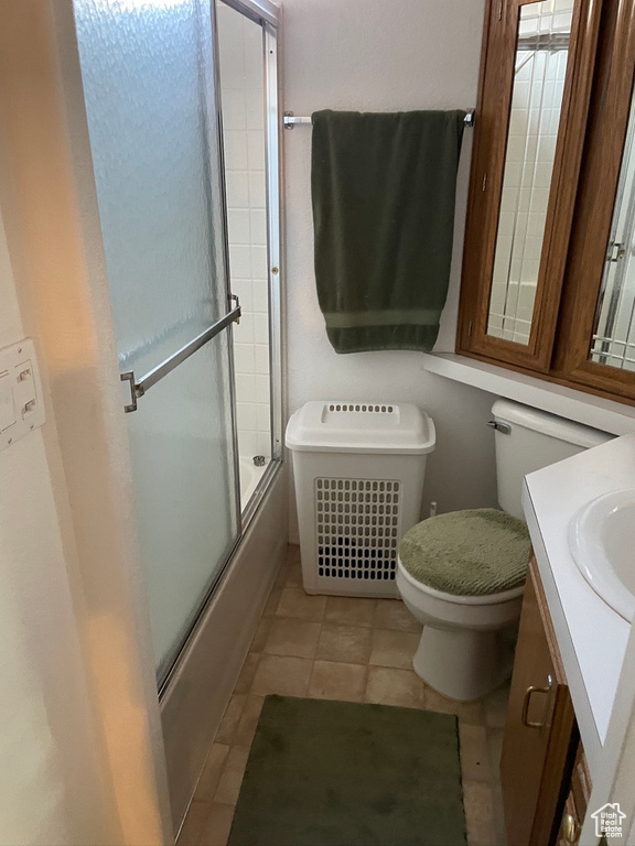 Full bathroom with large vanity, combined bath / shower with glass door, tile floors, and toilet