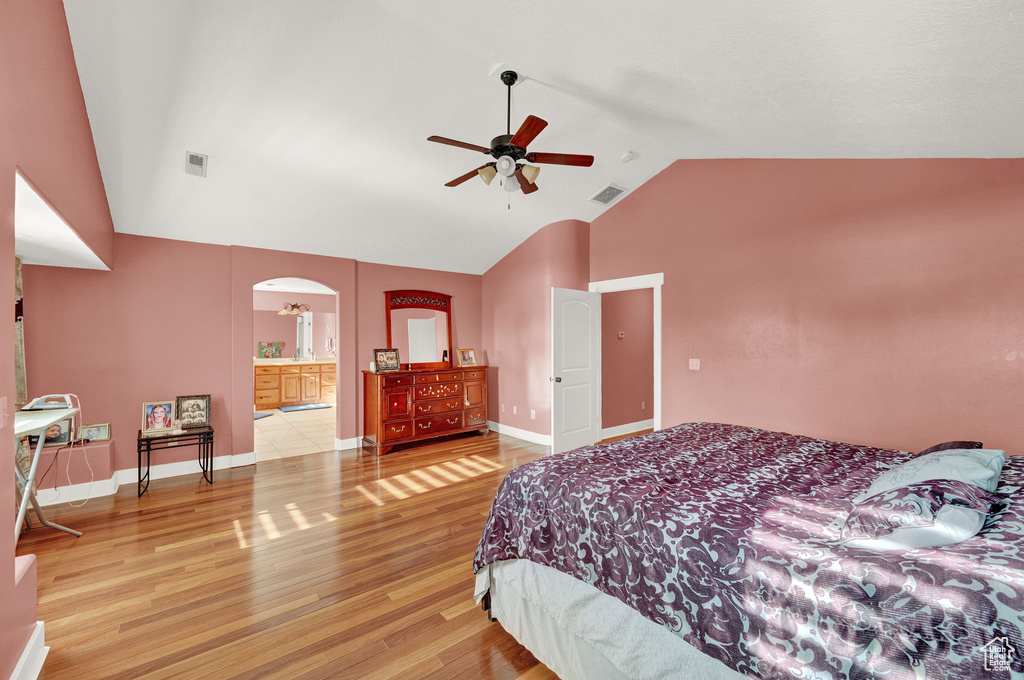 Bedroom featuring ensuite bath, vaulted ceiling, light hardwood / wood-style flooring, and ceiling fan