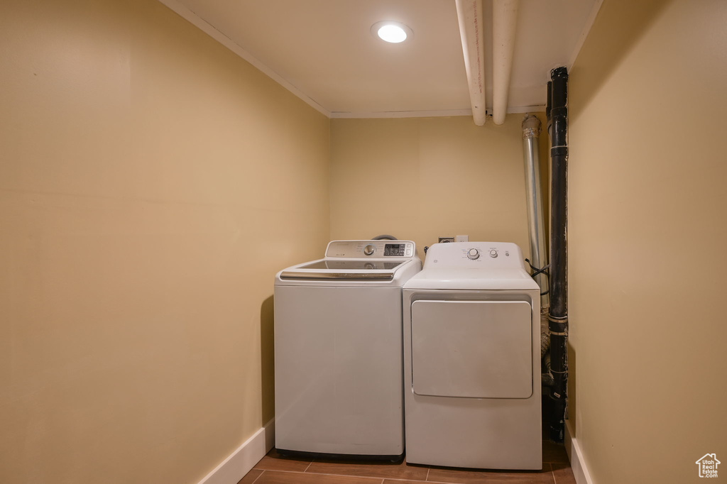 Laundry area featuring ornamental molding, washing machine and dryer, and light tile floors