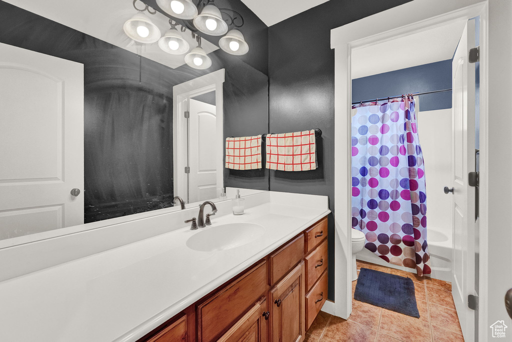 Full bathroom featuring vanity with extensive cabinet space, toilet, tile flooring, and shower / bath combo