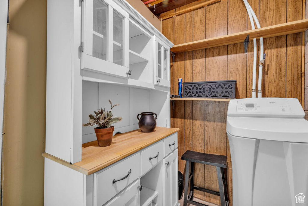 Laundry area with wood walls, washer / clothes dryer, and cabinets