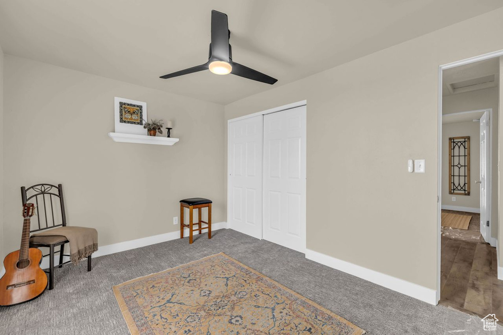 Sitting room featuring ceiling fan, baseboard heating, and dark colored carpet