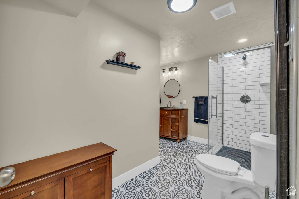 Bathroom with vanity, toilet, tiled shower, and tile flooring