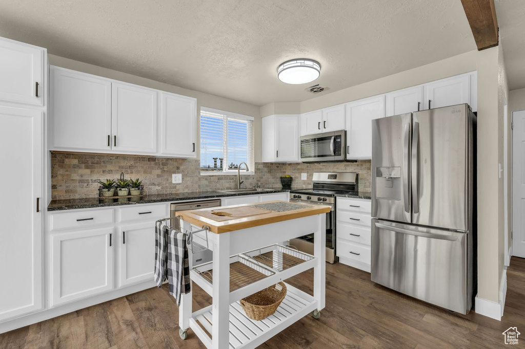 Kitchen featuring backsplash, sink, stainless steel appliances, and dark hardwood / wood-style flooring