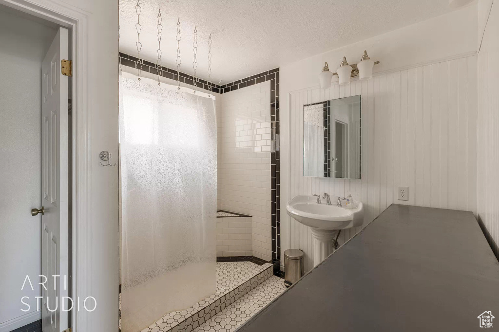 Bathroom featuring sink, a tile shower, and a textured ceiling
