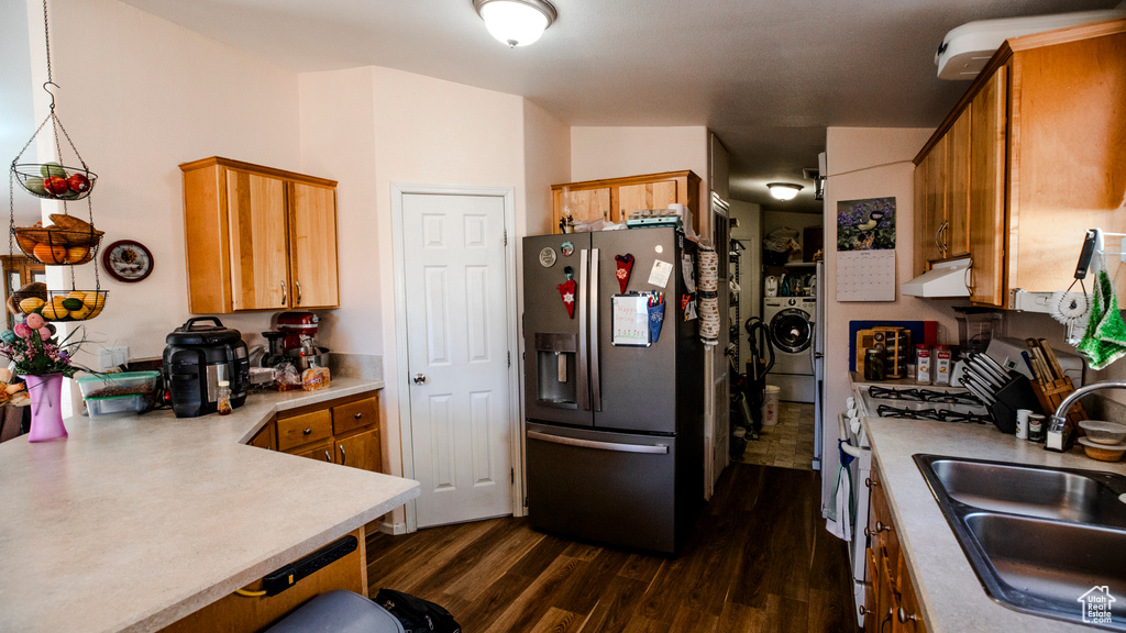Kitchen featuring range with gas stovetop, sink, dark wood-type flooring, washer / clothes dryer, and stainless steel refrigerator with ice dispenser