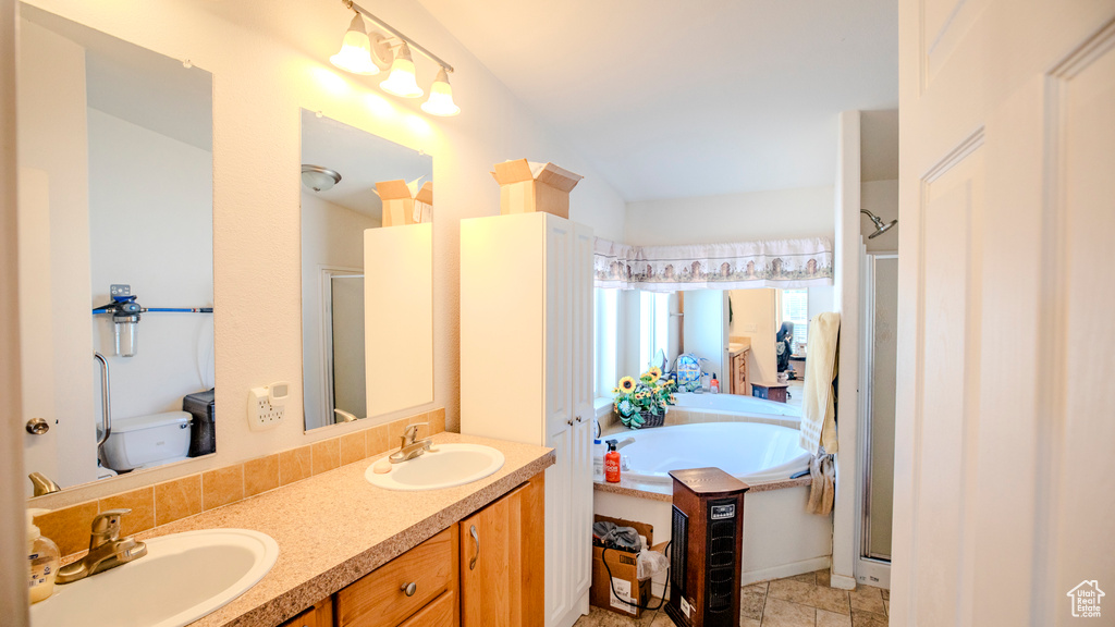 Bathroom with tile flooring, oversized vanity, independent shower and bath, and dual sinks