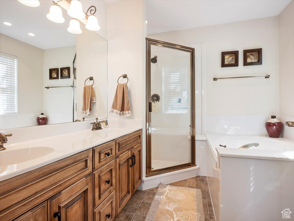 Bathroom with a chandelier, dual bowl vanity, tile floors, and plus walk in shower