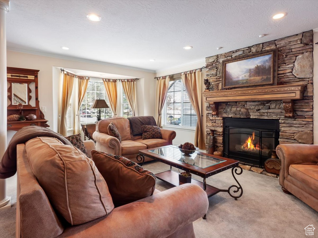 Carpeted living room featuring a fireplace, a textured ceiling, and ornamental molding