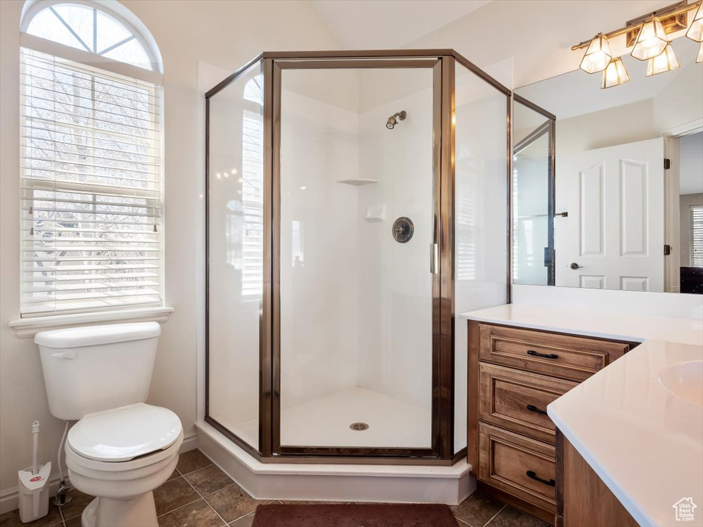 Bathroom featuring tile floors, toilet, vanity, and an enclosed shower